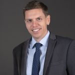 Man in suit with gray background.